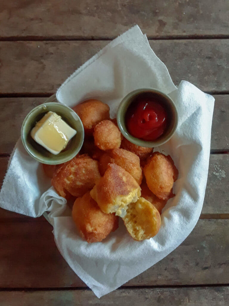 Hushpuppies in basket with butter and ketchup