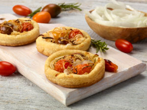 Sweet onion and tomato tarts on a cutting board