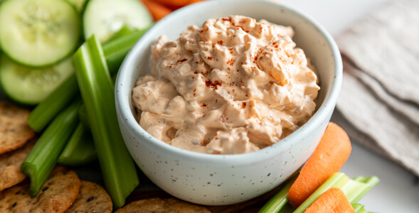 Creamy Onion Dip in white bowl surrounded by vegetables