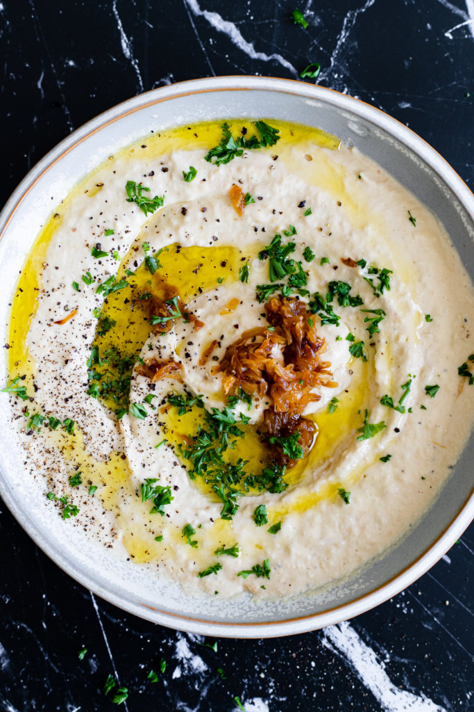 Bowl of Caramelized Onion Hummus on black background