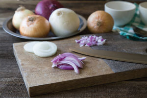 sliced onions on a cutting board with a knife