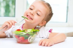 Little girl eating vegetable salad