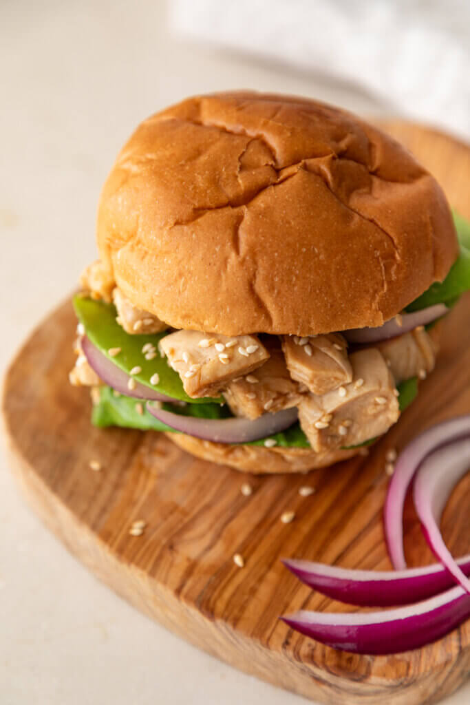 Chinese Chicken Salad Sandwich on cutting board with red onions