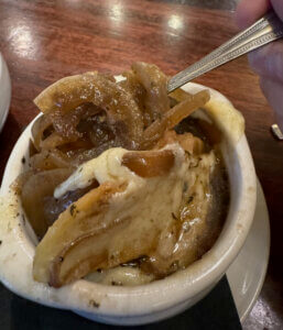 French Onion Soup with spoon in white bowl at The Tavern in Greeley