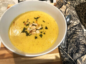 Almond, onion and saffron soup in a white bowl on a cutting board.