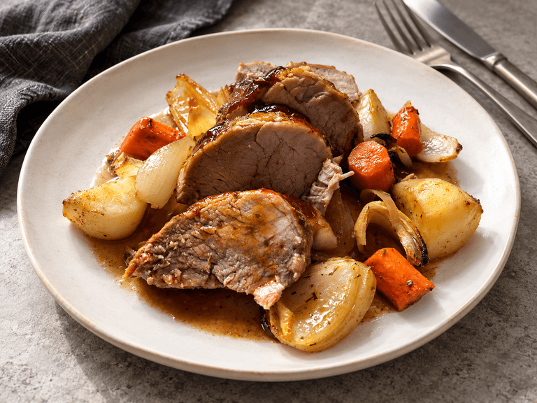 Plate of roasted pork loin with potatoes, onions and carrots